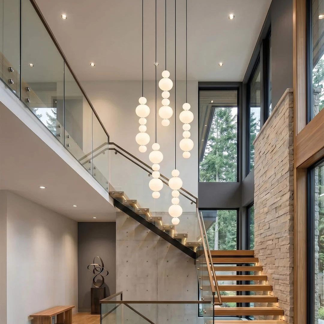 White Multi Globe Pendant Light for Staircase and High Ceiling installed beside a tall staircase with glass railing
